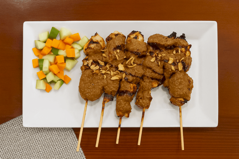 Batavia's Sate Ayam, a must-try dish featuring succulent chicken skewers and a delectable peanut sauce